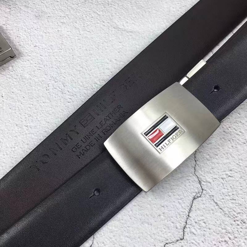 Close up detail of Tommy Hilfiger silver plaque belt buckle with flag logo and embossed genuine leather branding