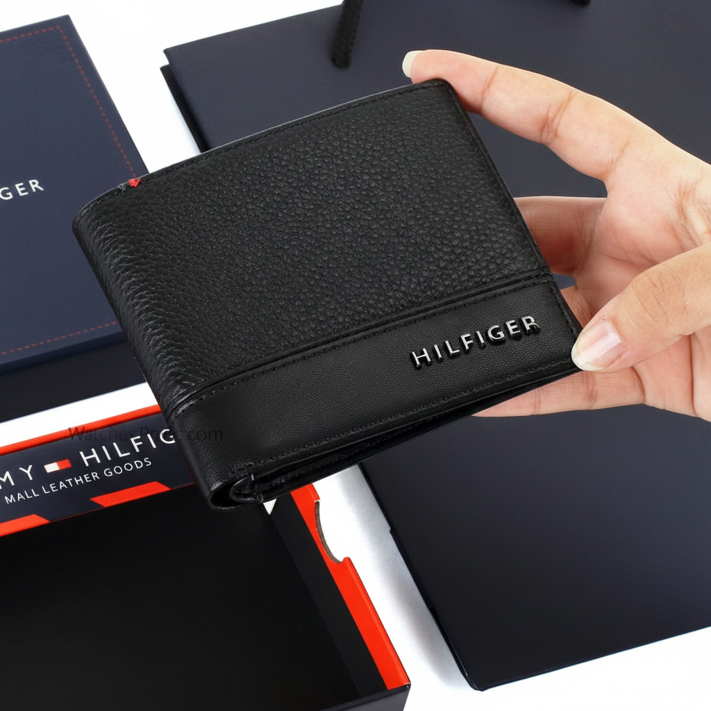 Hand holding a Tommy Hilfiger black men's wallet featuring a mix of pebble and smooth leather with a raised silver metal logo