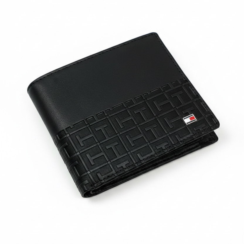 Angled view of Tommy Hilfiger black leather wallet featuring smooth top panel and geometric monogram embossed bottom with flag logo