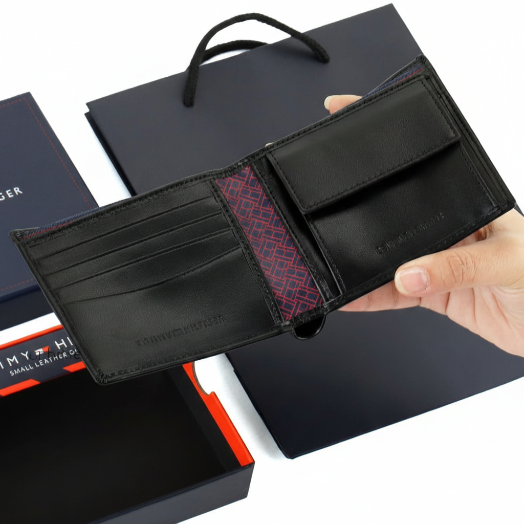Interior view of Tommy Hilfiger black wallet showing a snap-button coin pocket, card slots, and a unique monogram pattern lining in the center