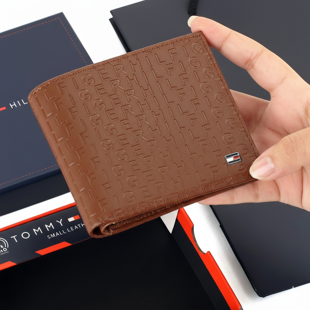 Handheld view of a Tommy Hilfiger men's brown leather wallet, showing its compact size and the tactile embossed designer branding