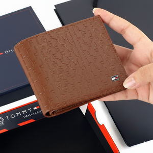 Handheld view of a Tommy Hilfiger men's brown leather wallet, showing its compact size and the tactile embossed designer branding