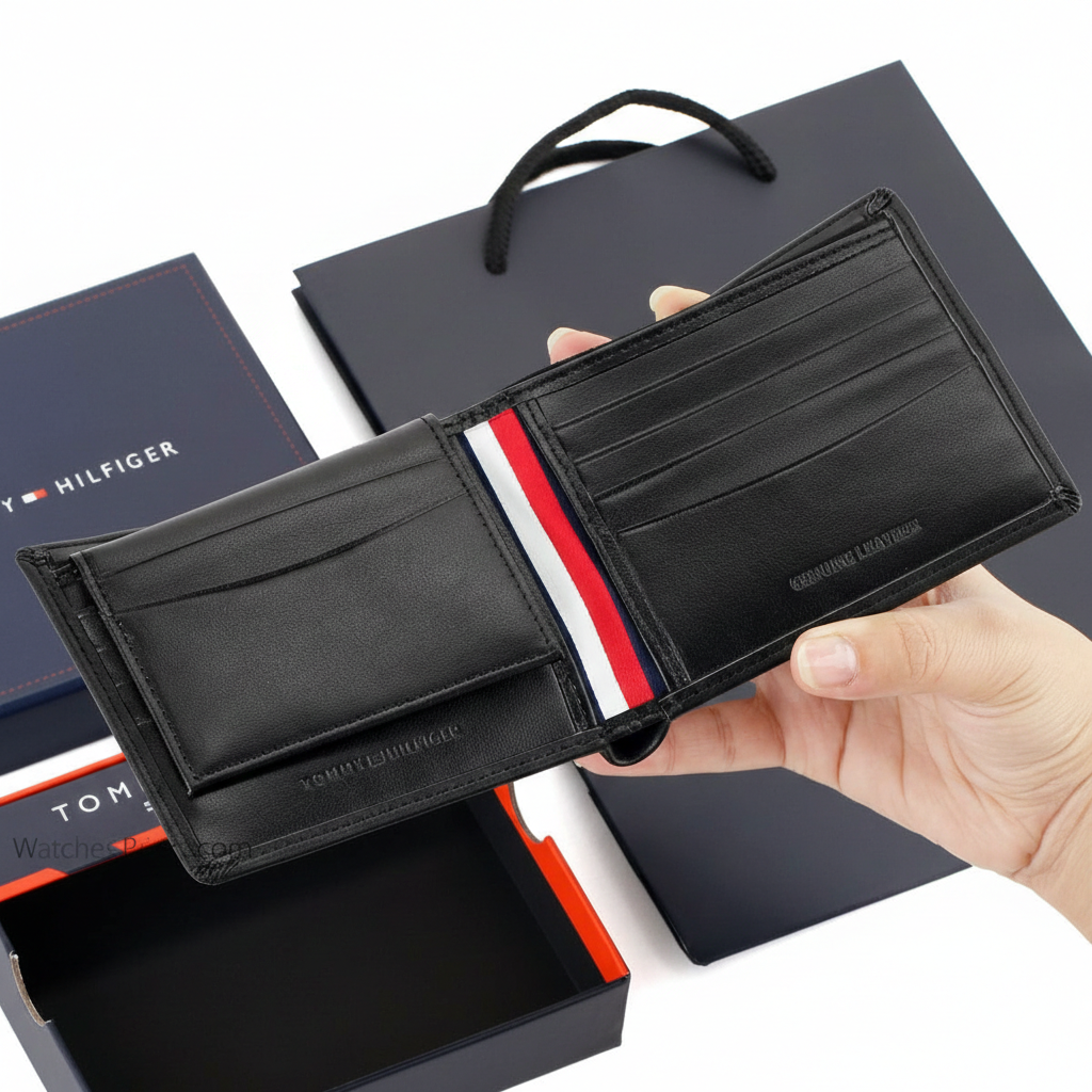 Handheld view of an open Tommy Hilfiger black leather wallet highlighting the iconic red, white, and blue interior flag ribbon and card slots