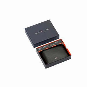 Authentic Tommy Hilfiger men's black genuine leather bifold wallet featuring an all-over embossed monogram pattern and silver metal logo, presented in a premium navy gift box