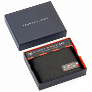 Authentic Tommy Hilfiger men's black Saffiano leather bifold wallet featuring a signature fabric logo patch, presented in its premium navy branded gift box
