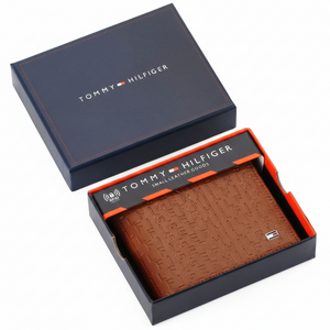 Authentic Tommy Hilfiger men's brown genuine leather bifold wallet featuring an all-over embossed logo pattern, presented in a premium navy gift box