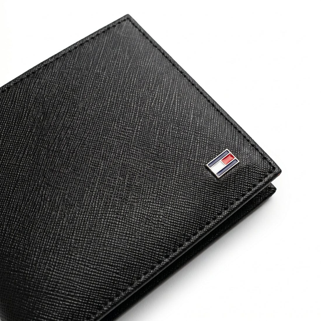 Live professional angled product photograph of the sleek Tommy Hilfiger smooth black leather bifold wallet over clean white background