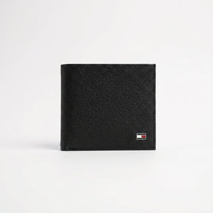 Live front view smartphone photograph of the Tommy Hilfiger smooth black leather wallet highlighting the tiny iconic enamel flag metal logo corner accent