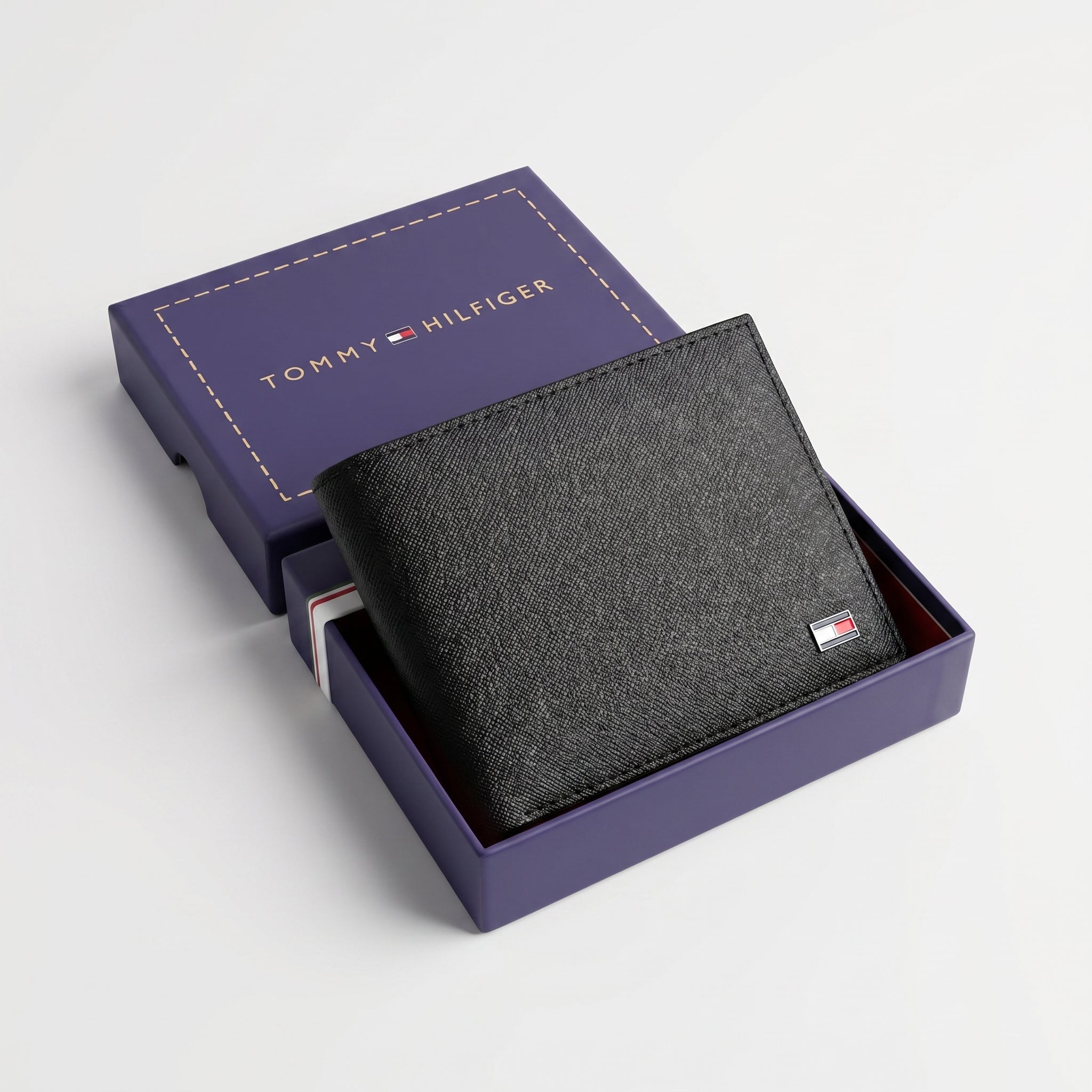 Top-down studio product photography of the Tommy Hilfiger mirror original textured black leather wallet neatly resting inside its open premium navy branded gift box