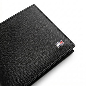 Macro close-up studio shot focusing on the iconic Tommy Hilfiger enamel flag metal logo accent over the black saffiano textured genuine leather surface