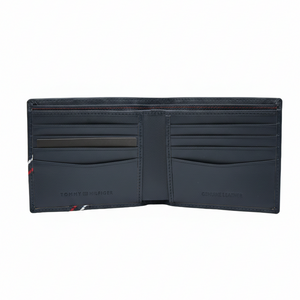 Angled closed view of Tommy Hilfiger navy blue men's wallet highlighting smooth leather and signature tricolor diagonal stripe on the corner