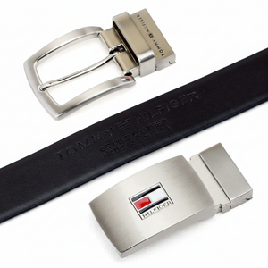 Close-up detail of the Tommy Hilfiger reversible belt in brown leather, featuring an embossed logo on the strap and two premium interchangeable metal buckles