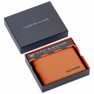 Tommy Hilfiger men's tan embossed leather wallet with monogram pattern presented inside its original navy blue branded gift box