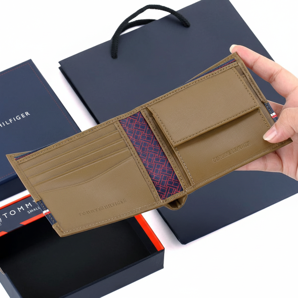 Handheld view of the open Tommy Hilfiger tan leather wallet alongside its branded gift box and luxury shopping bag