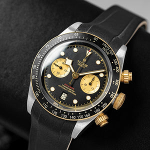 Tudor Black Bay Chrono S&G men's chronograph watch, 41mm steel and yellow gold case, champagne chronograph counters, black rubber strap – angle view on dark background