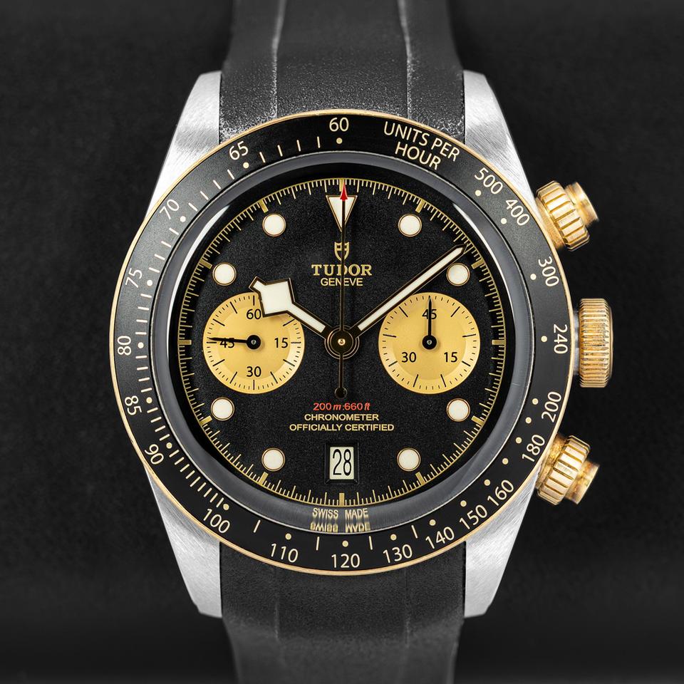 Tudor Black Bay Chrono S&G men's chronograph watch, 41mm steel and yellow gold case, champagne chronograph counters, black rubber strap – front view on dark background
