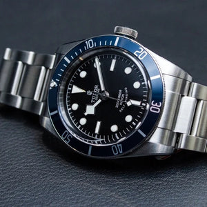 Tudor Black Bay M79230B-0008 men's automatic dive watch, 41mm stainless steel case, black dial, blue bezel, steel bracelet – angle view on dark background