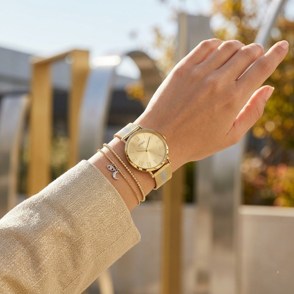 Close up of Guess U1155L3 women's quartz battery watch on wrist showing clean gold dial and gold roman numerals