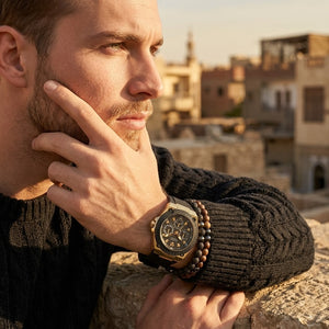 Elegant man wearing Guess Legacy W1049G5 men's quartz battery watch with gold case and luxury black rubber strap