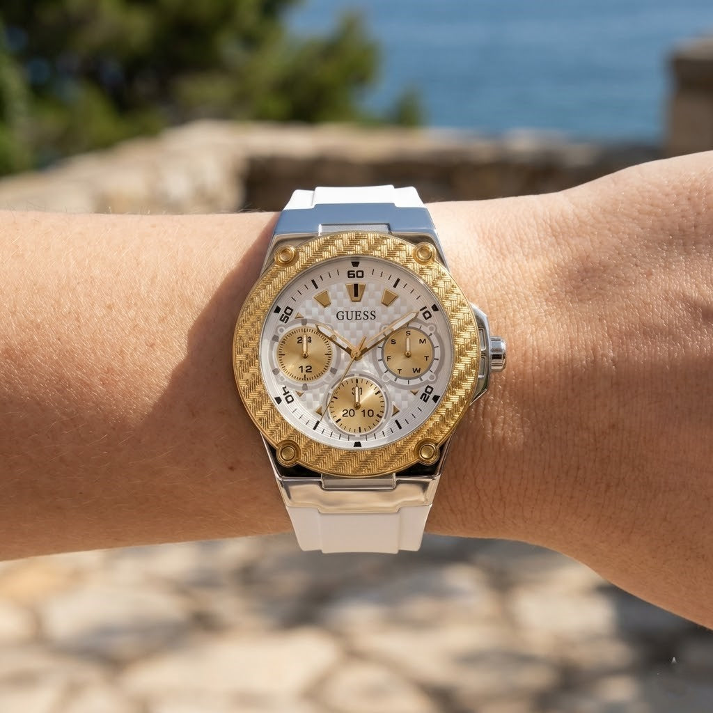 Close up of Guess Zena W1094L1 women's quartz battery watch on wrist showing clean white dial and luxury gold bezel