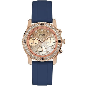 Guess Confetti Multi-Function W1098L6 women's watch with cushion-shaped gold-tone case, dynamic bezel embellished with crystals and screw details, deep navy blue dial with luminous yellow gold hands and indices, and integrated flexible navy blue silicone rubber strap main view