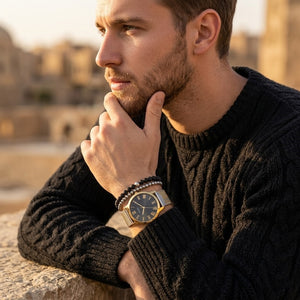 Elegant man wearing Guess W1179G2 men's quartz battery watch with gold case and luxury striped mesh bracelet