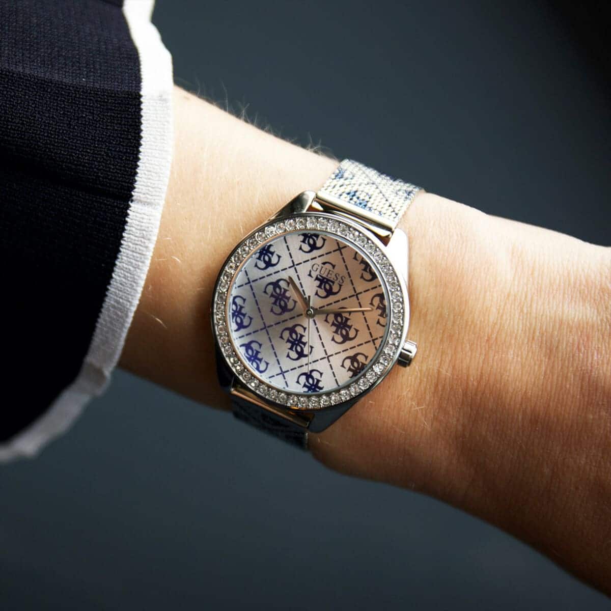 Close up of Guess Claudia W1279L1 women's quartz battery watch on wrist showing blue 4G logo pattern dial and luxury crystal bezel