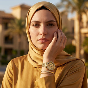 Elegant woman wearing Guess Claudia W1279L2 women's quartz battery watch with gold case and luxury printed mesh bracelet