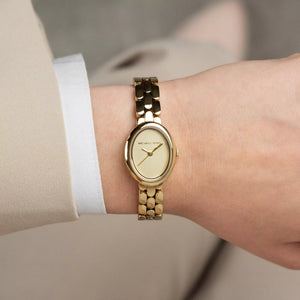 Gold watch on a wrist with a neutral background