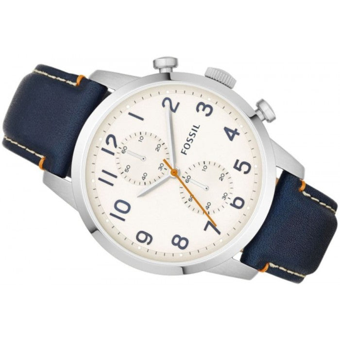 Fossil wristwatch with a silver-tone stainless steel case, a cream-colored dial with navy blue Arabic numerals and sub-dials, and a dark navy blue leather strap with orange stitching.